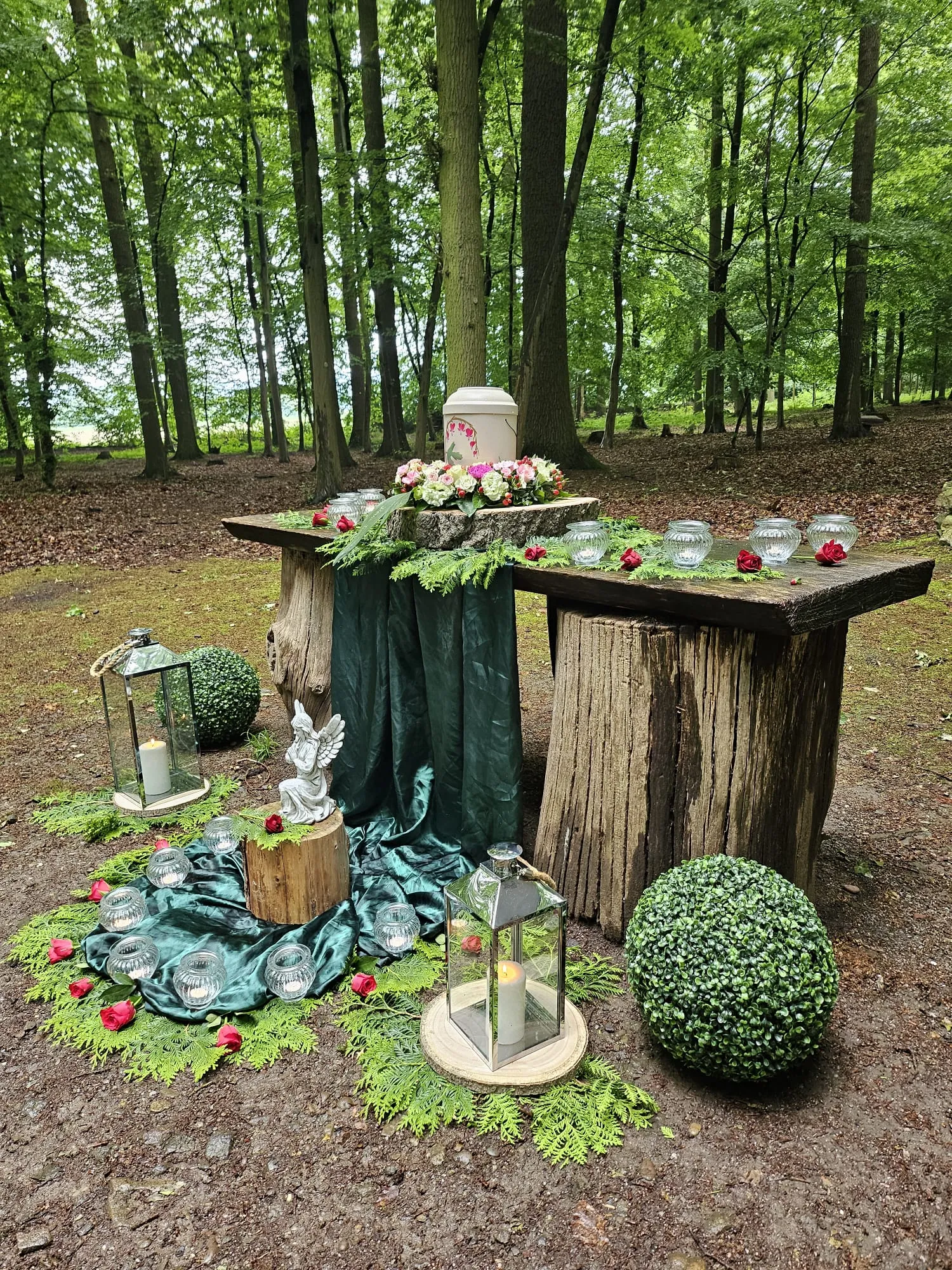 Urne unter einem Baum im Garten mit Sonnenblumen und Kerzen