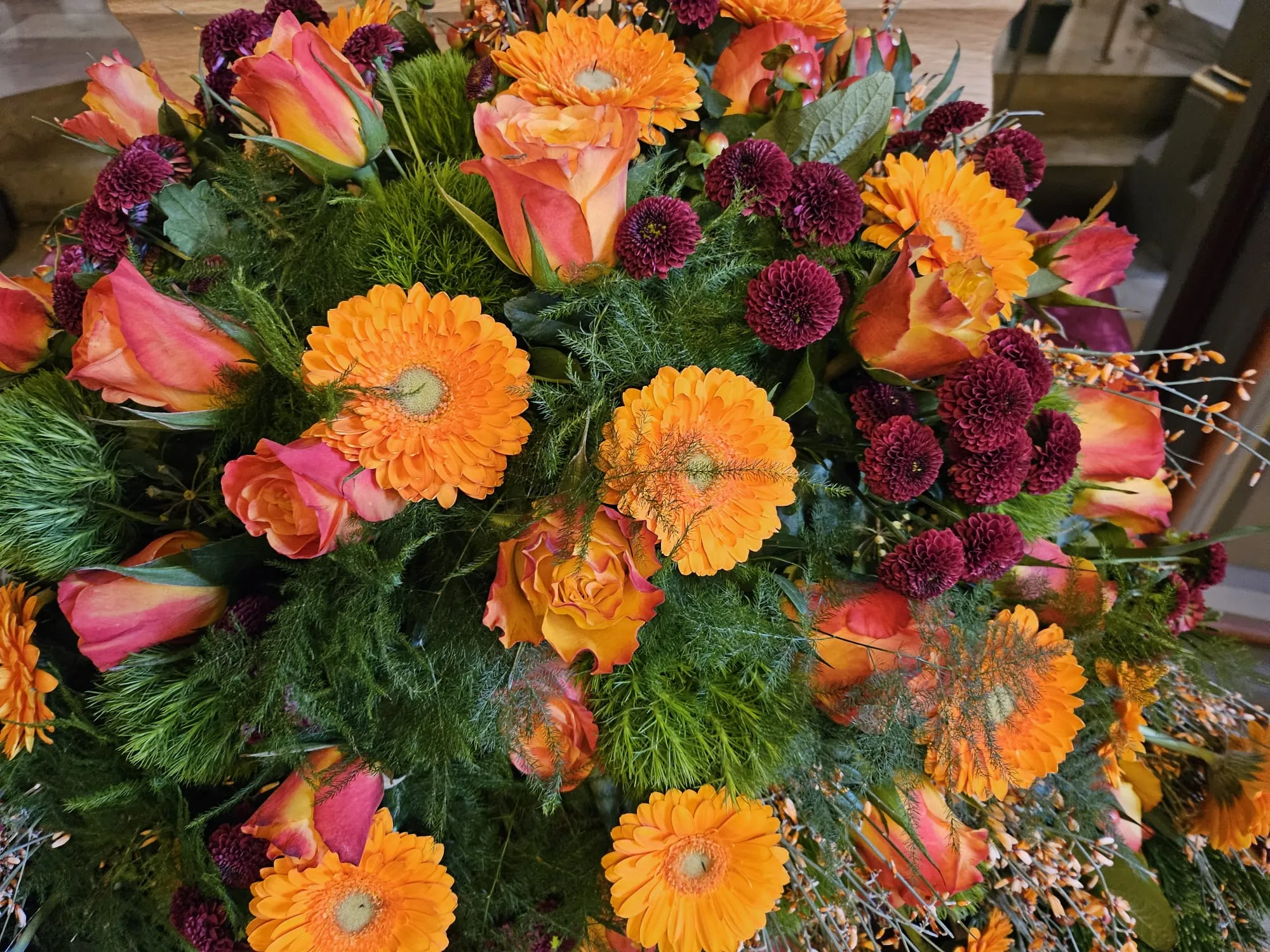 Farbenfroher Trauerkranz aus orangefarbenen Gerbera und Rosen