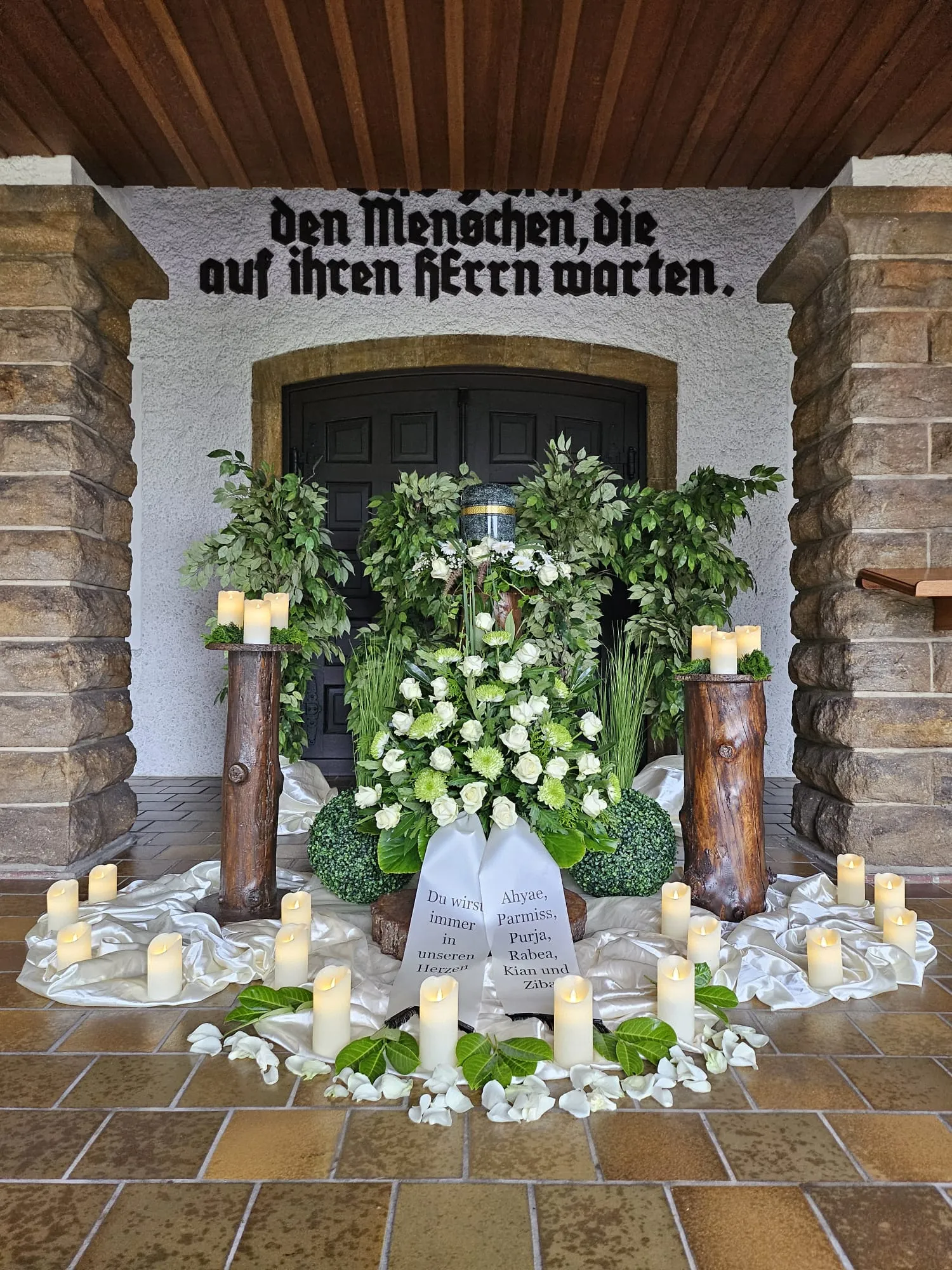 Urne mit üppigem weißem Blumenschmuck am Eingang der Trauerhalle